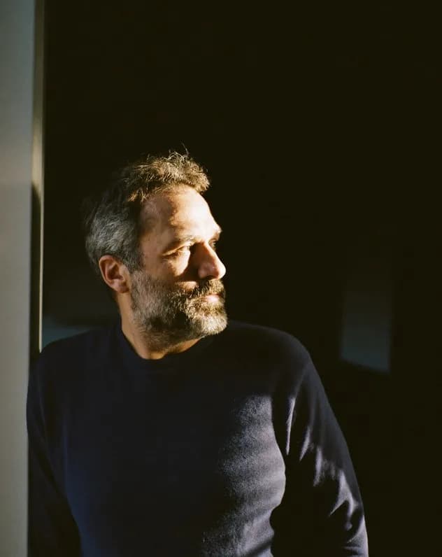Portrait of a man in a dark sweater standing in soft window light